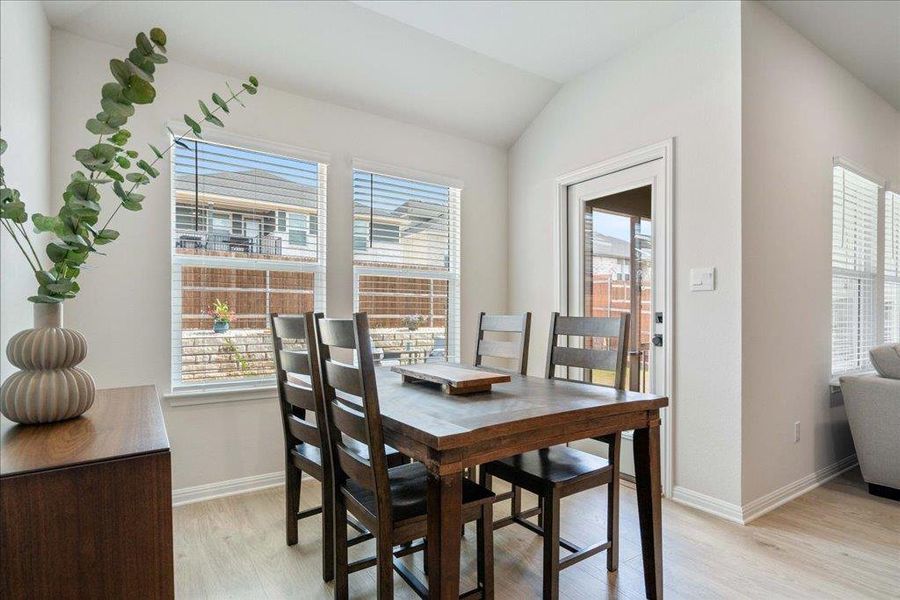Dining room with light wood-style flooring, baseboards, and vaulted ceiling