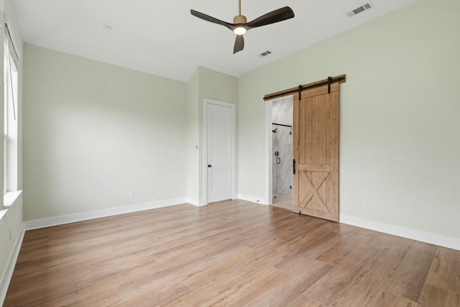 The Primary Bedroom offers exceptional space and versatility, easily accommodating a king-sized bed, matching nightstands, a dresser, and a dedicated media area. Thoughtfully designed for both comfort and functionality, the room provides a tranquil retreat with ample room to create your ideal sanctuary. A stylish barn door serves as an eye-catching architectural feature, offering seamless access to the luxurious Ensuite Bath while adding warmth, character, and designer appeal.