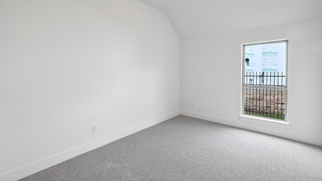 Carpeted spare room with vaulted ceiling and baseboards Carpeted spare room with vaulted ceiling and baseboards