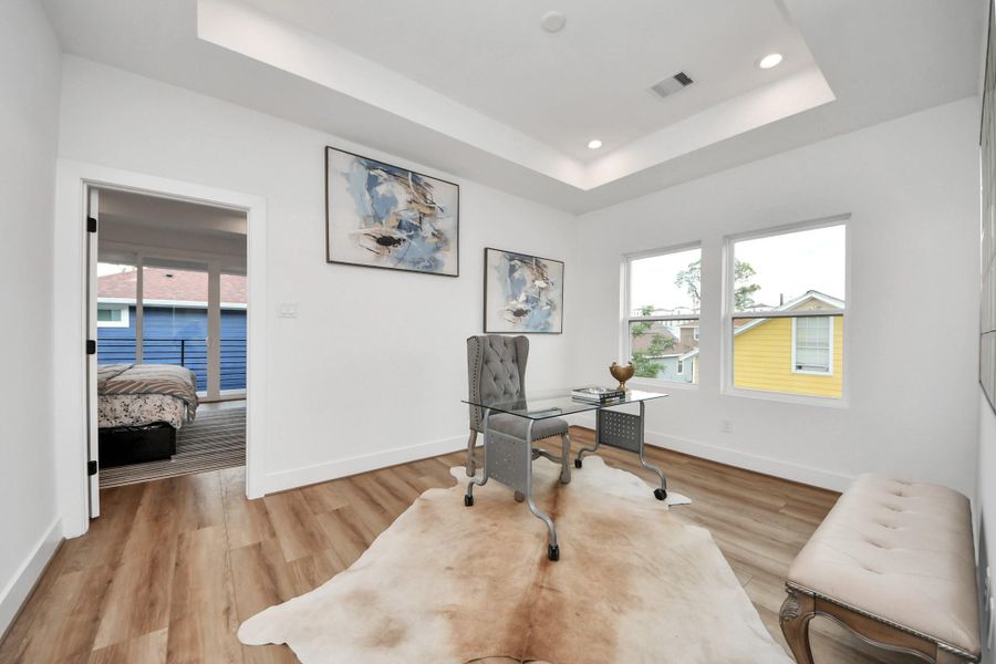 This bright and inviting office space features sleek wood flooring, stylish decor, and ample natural light, creating the perfect environment for productivity and inspiration.