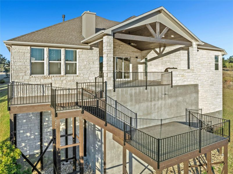 Back of house with a patio, roof with shingles, a balcony, and stone siding Back of house with a patio, roof with shingles, a balcony, and stone siding