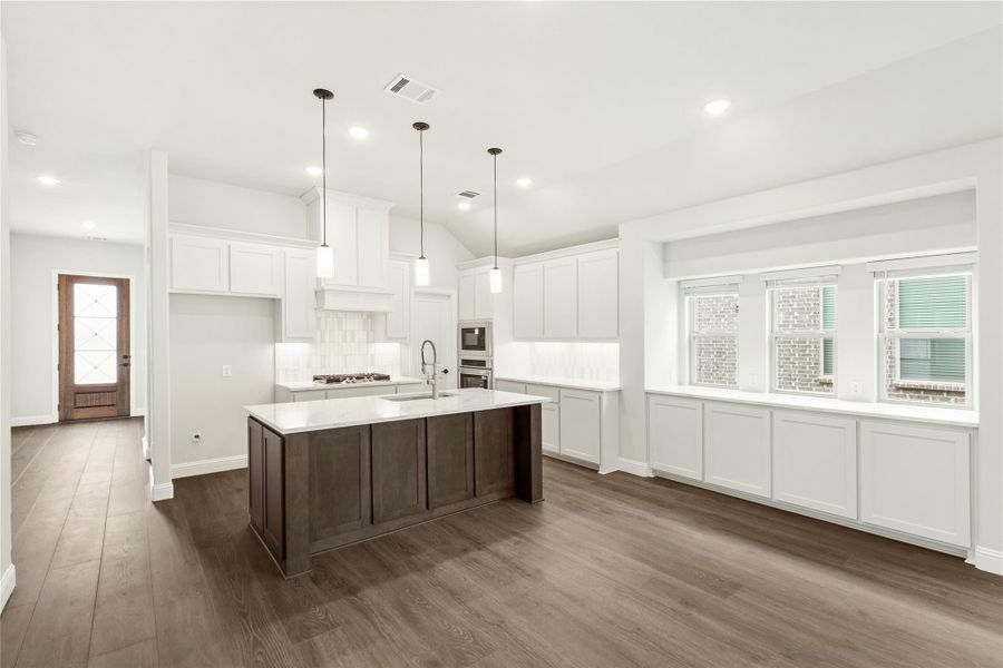 Open kitchen with white cabinets, dark wood island, pendant lights, and hardwood floors Open kitchen with white cabinets, dark wood island, pendant lights, and hardwood floors
