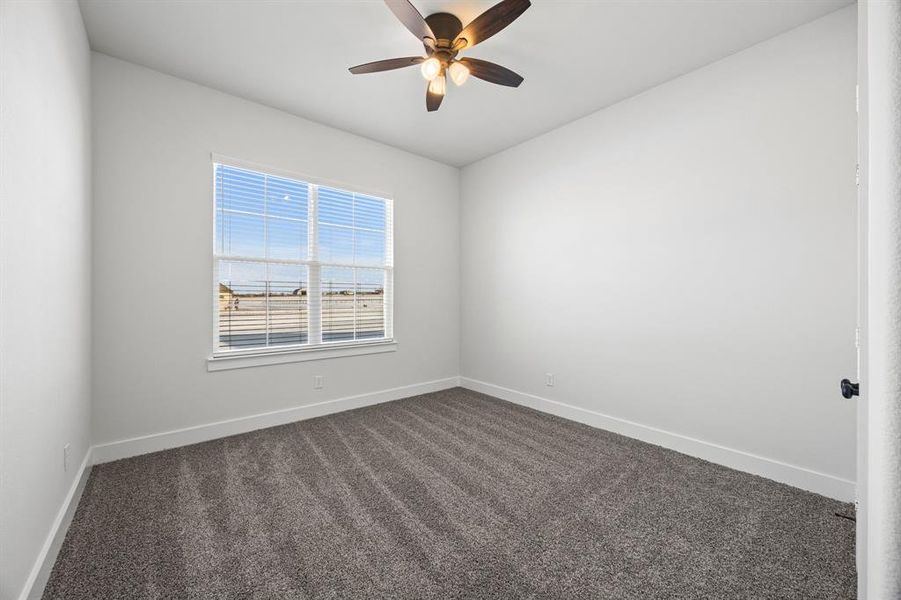 Spare room featuring dark colored carpet and ceiling fan