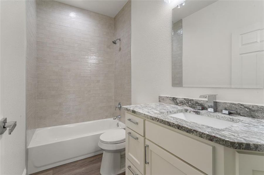 Bathroom featuring a white vanity with slab cabinet doors, a drop-in sink, and a speckled countertop