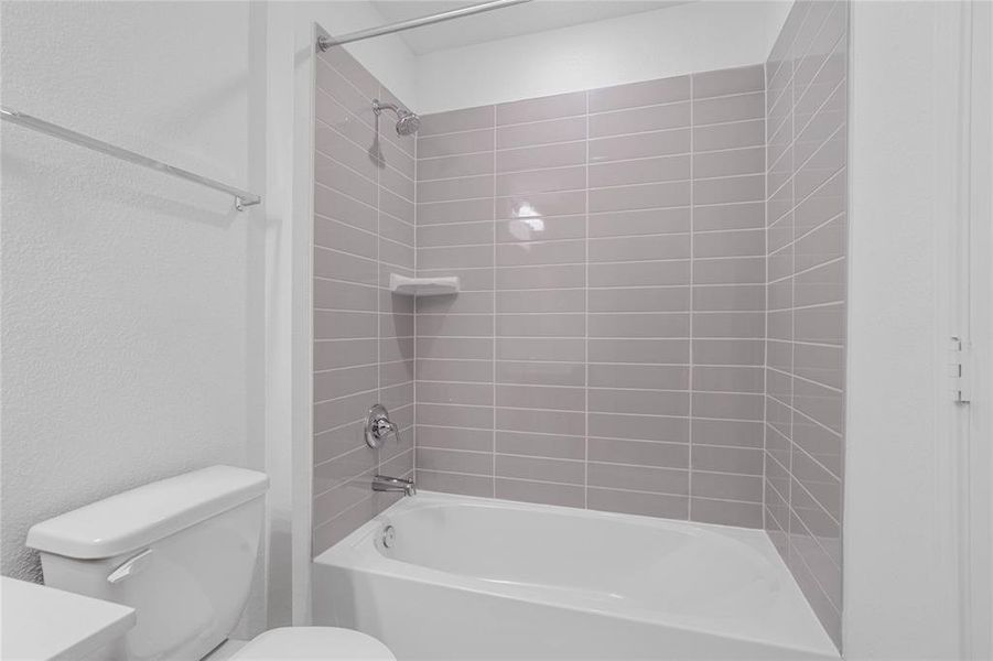 Additional view of secondary bath featuring the bath/shower combo with tile surround, dark, sleek fixtures and modern finishes.