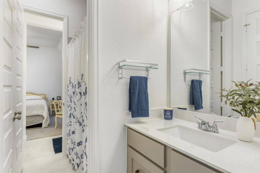 Bathroom featuring a shower with curtain, vanity, connected bathroom, and light tile patterned floors