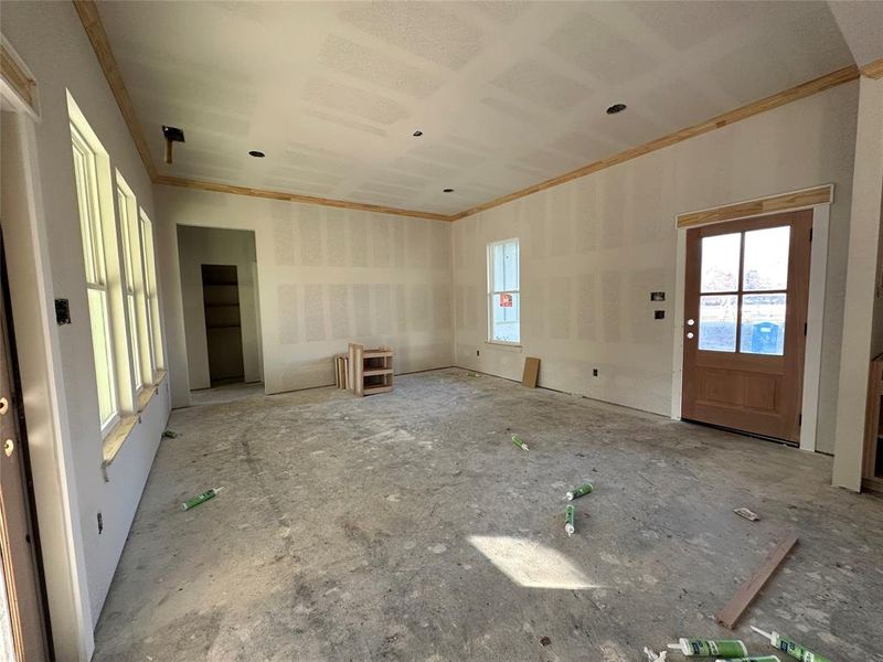 Unfurnished living room with heating unit and ornamental molding