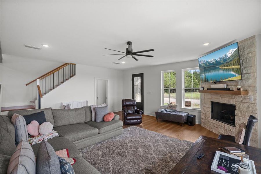 Living room with wood finished floors, stairway, ceiling fan, a fireplace, and recessed lighting Living room with wood finished floors, stairway, ceiling fan, a fireplace, and recessed lighting