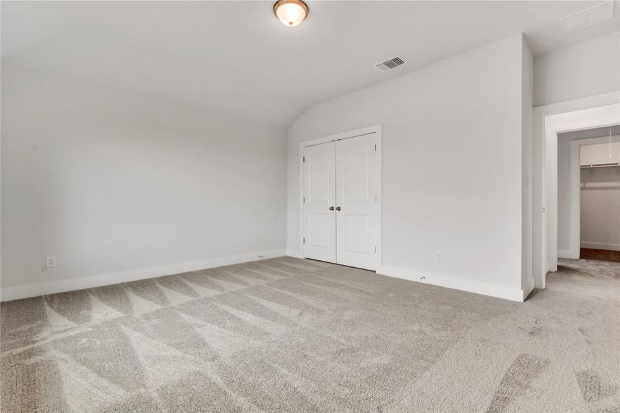 A spacious, naturally illuminated room featuring plush carpeting and convenient closet storage.