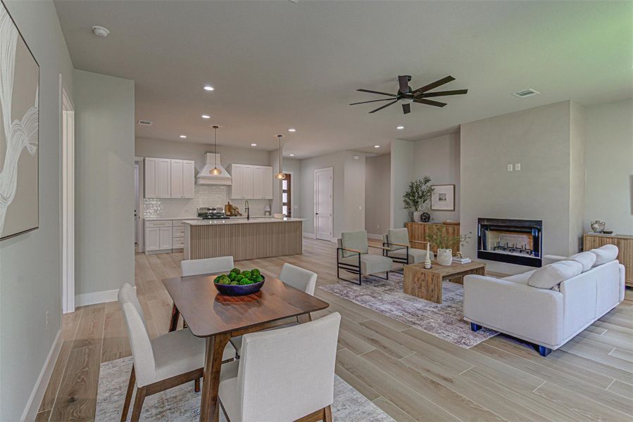 Dining room featuring light wood-style floors, a fireplace, ceiling fan, recessed lighting, and baseboards
