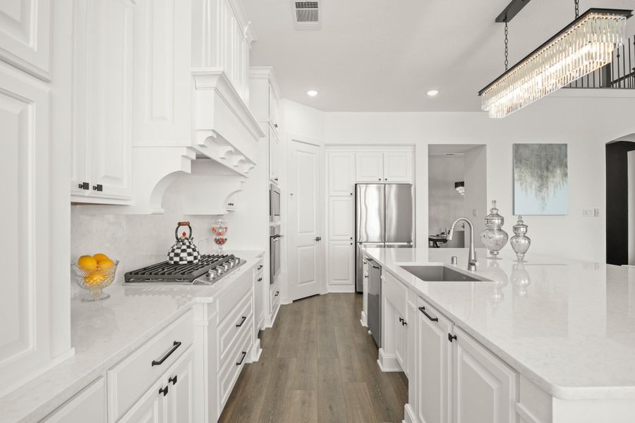 The kitchen includes an Electrolux stainless steel appliance package, complete with a five-burner gas cooktop and a custom decorative vent hood with cabinetry above.