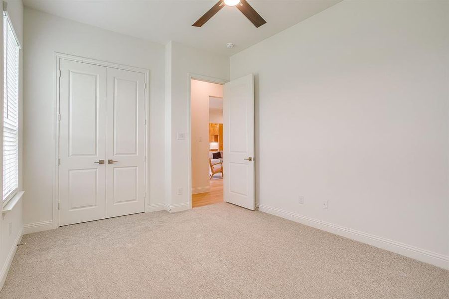 Secondary bedroom with ceiling fan and walk in closet