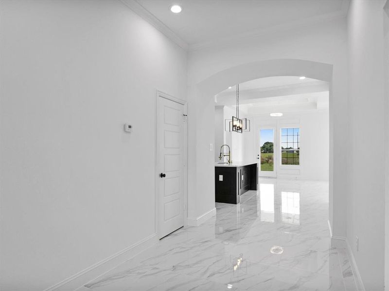Corridor with baseboards, arched walkways, ornamental molding, a chandelier, and recessed lighting