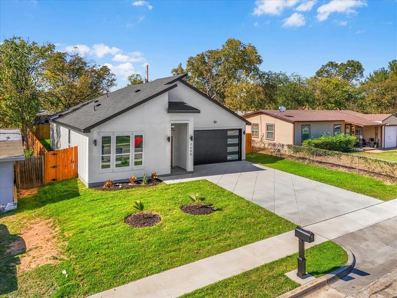 View of front of home featuring concrete driveway, stucco siding, a shingled roof, and a gate
