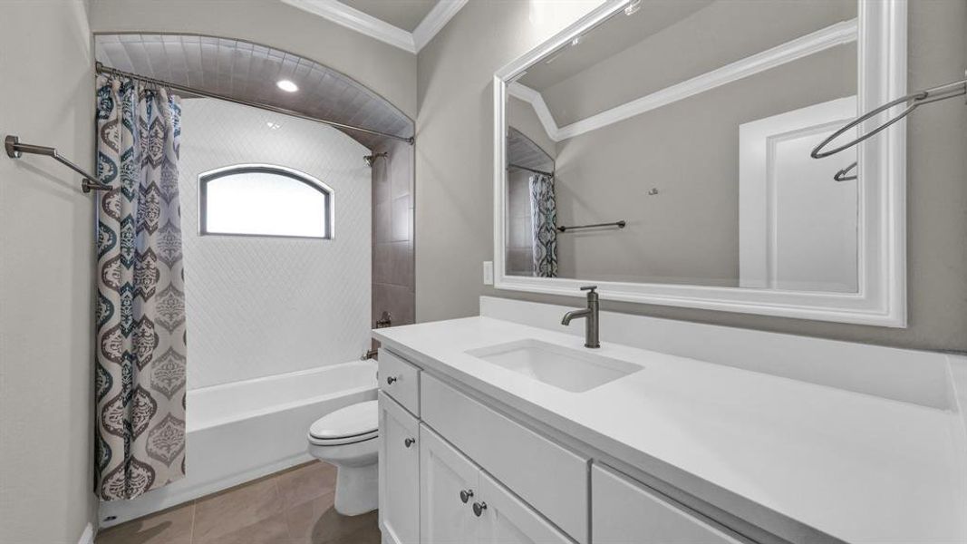 Full bathroom featuring tile patterned flooring, shower / bath combo, toilet, vanity, and ornamental molding