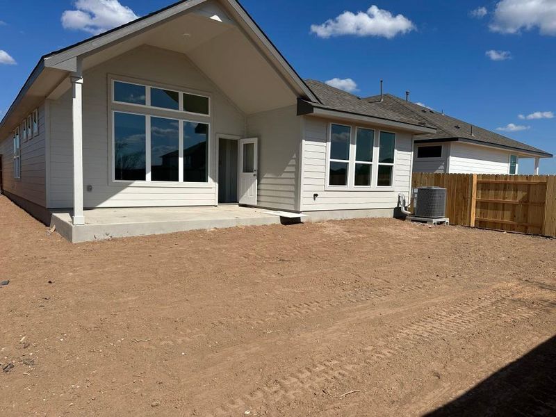 Rear view of house featuring a patio area and a shingled roof