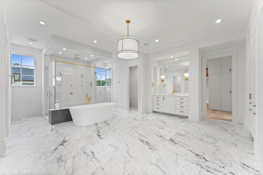 Encased in marble, the primary bathroom is fully equipped with double vanities and water closet Encased in marble, the primary bathroom is fully equipped with double vanities and water closet