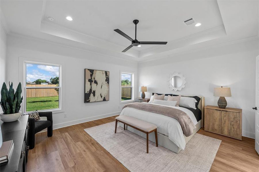 Bedroom featuring a raised ceiling, crown molding, light wood-style flooring, recessed lighting, and ceiling fan