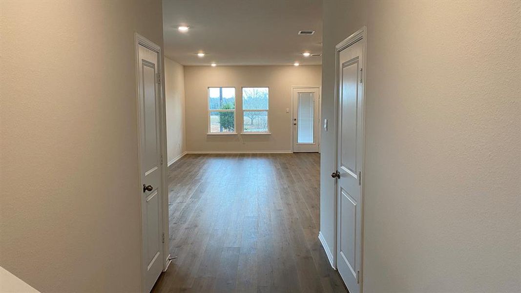 Corridor featuring dark wood-style floors, a textured wall, and recessed lighting