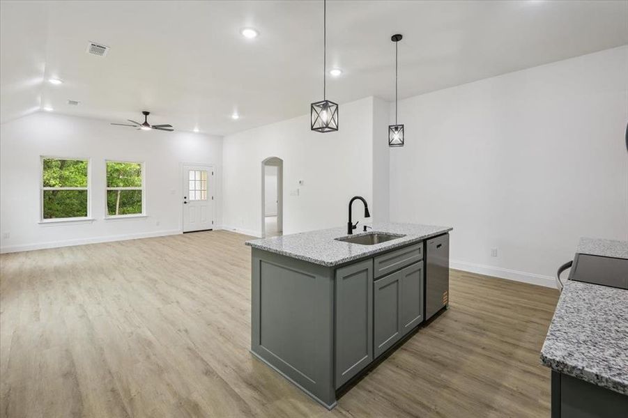 Kitchen with decorative light fixtures, arched walkways, gray cabinets, recessed lighting, and light stone counters Kitchen with decorative light fixtures, arched walkways, gray cabinets, recessed lighting, and light stone counters