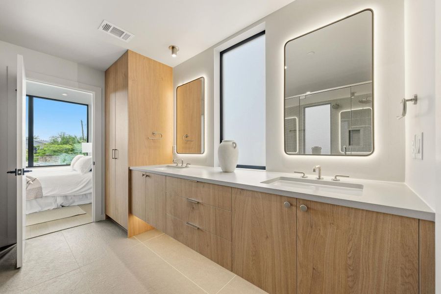 A well-appointed primary bathroom showcases dual vanities with illuminated mirrors and ample storage. A well-appointed primary bathroom showcases dual vanities with illuminated mirrors and ample storage.