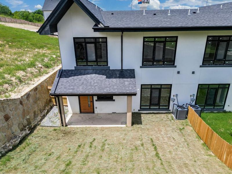 Contemporary exterior with multiple large windows, a covered patio featuring a wood-panel door, and a stone retaining wall Contemporary exterior with multiple large windows, a covered patio featuring a wood-panel door, and a stone retaining wall