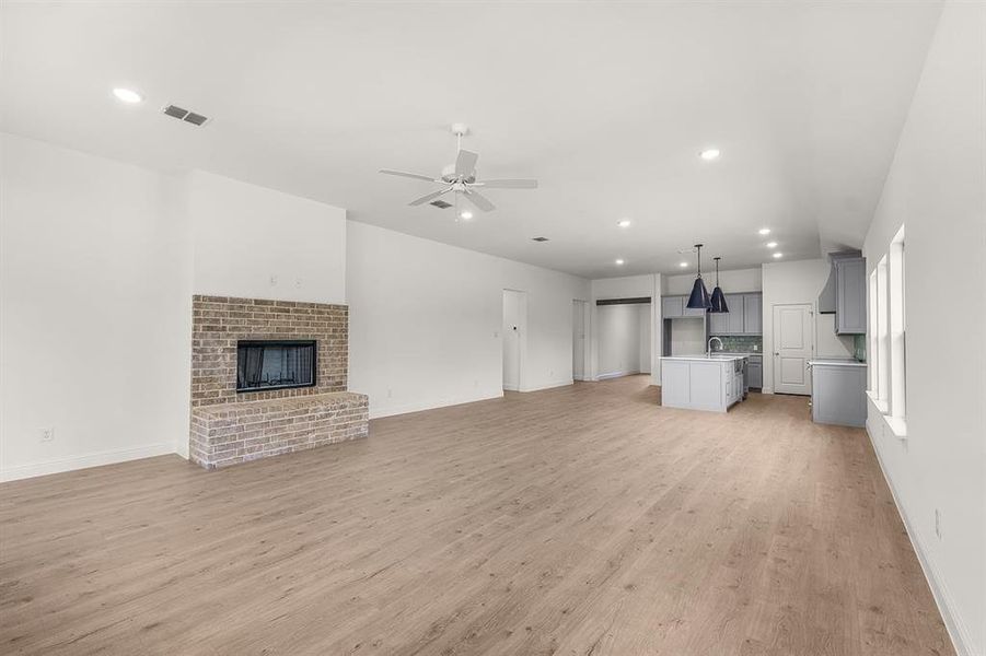 Unfurnished living room featuring recessed lighting, a fireplace, light floors, and ceiling fan
