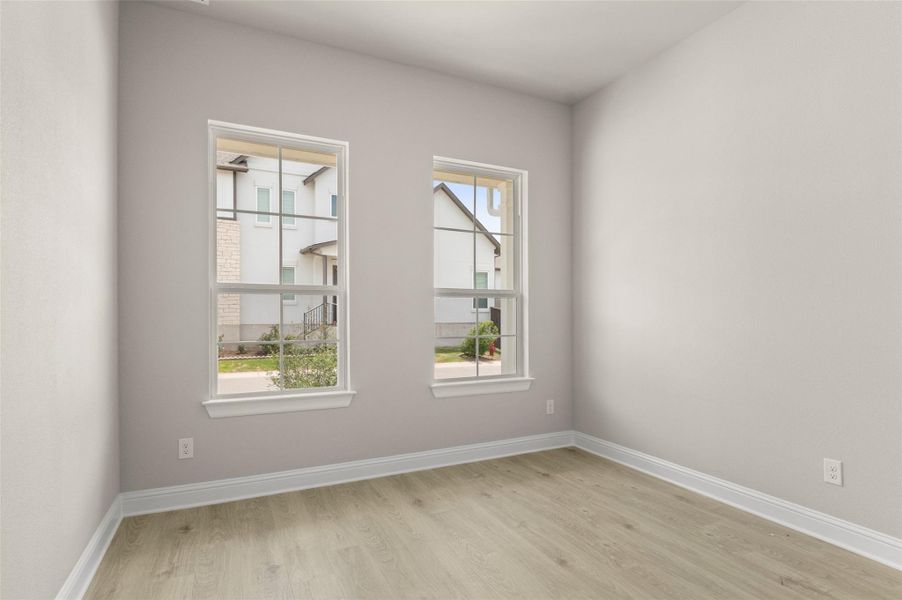 Unfurnished room with light wood-style floors, healthy amount of natural light, and baseboards