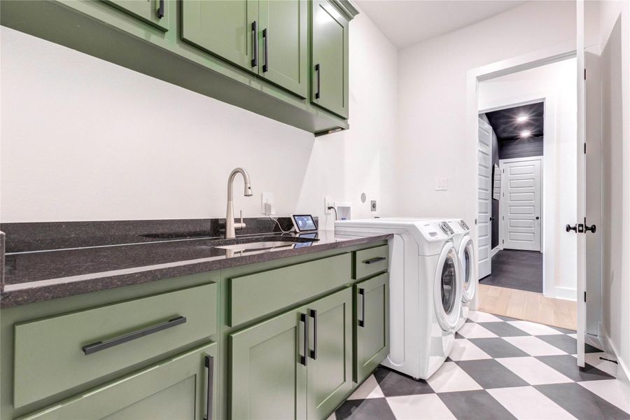 This laundry room features stylish green cabinetry, a sleek black countertop, and modern appliances. The space is well-lit and has a checkered floor, offering a functional and attractive area for laundry tasks. This laundry room features stylish green cabinetry, a sleek black countertop, and modern appliances. The space is well-lit and has a checkered floor, offering a functional and attractive area for laundry tasks.
