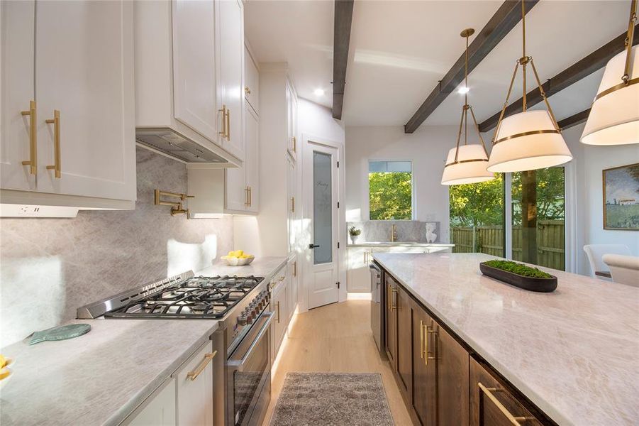 Kitchen with high end stove, light stone counters, beamed ceiling, backsplash, and pendant lighting