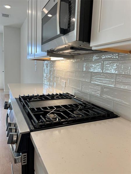 Kitchen with range with gas cooktop, tasteful backsplash, light stone counters, and recessed lighting