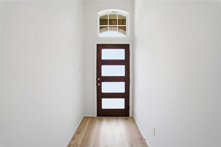 Doorway featuring wood finished floors and a high ceiling