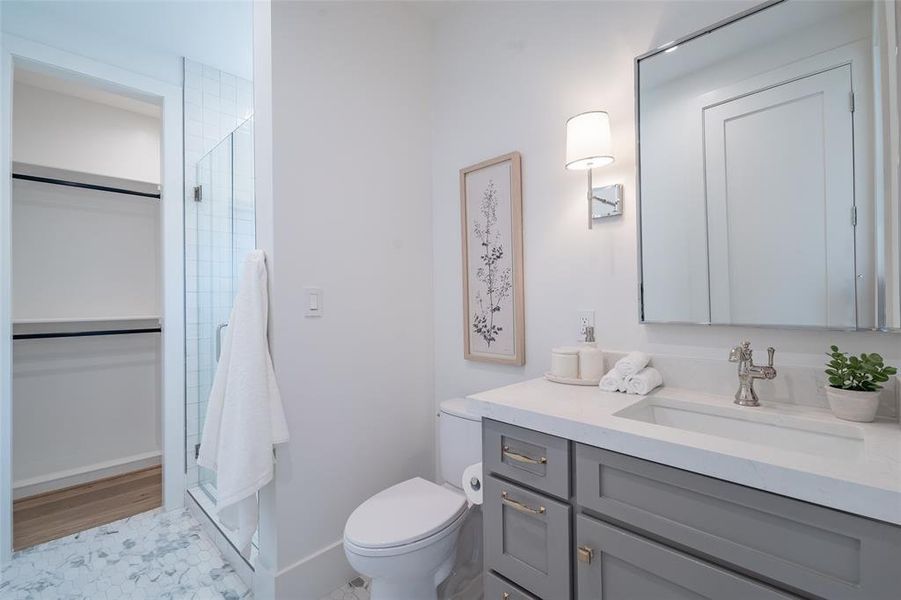 Bathroom with an enclosed shower, toilet, vanity, and walk-in closet