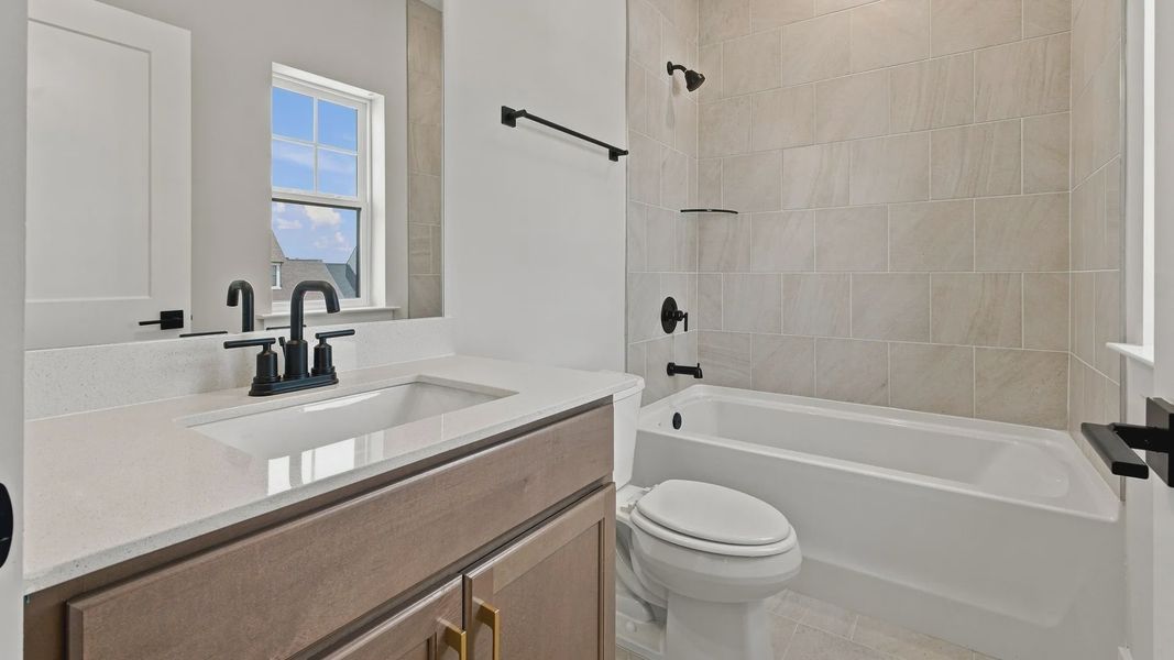Upstairs bathroom connected to bedroom with bathtub and window for natural light.