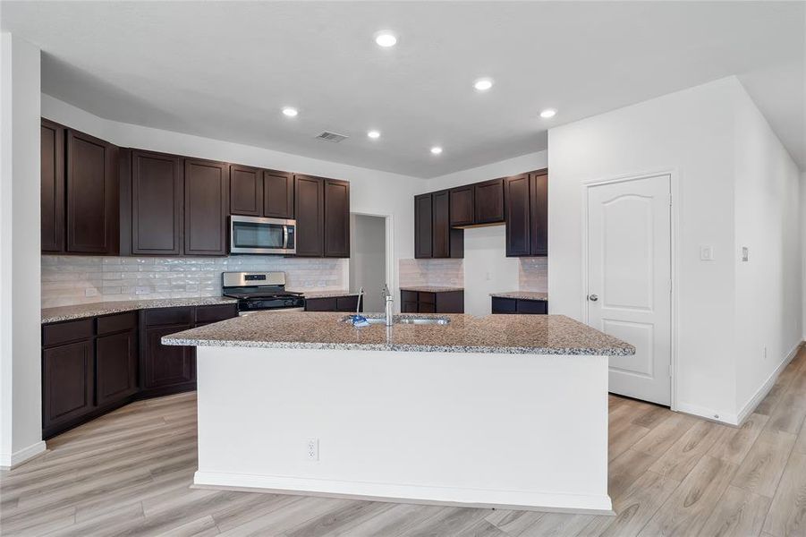 This kitchen is by far any chef’s dream! This spacious kitchen features high ceilings, dark stained wood cabinets, granite countertops, SS appliances, modern tile backsplash, recessed lighting, extended counter space, granite kitchen island with double sink and space for breakfast bar, and a walk-in pantry all overlooking your huge family room.