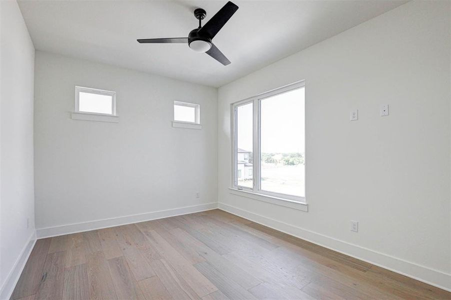 Empty room with ceiling fan and light hardwood / wood-style flooring