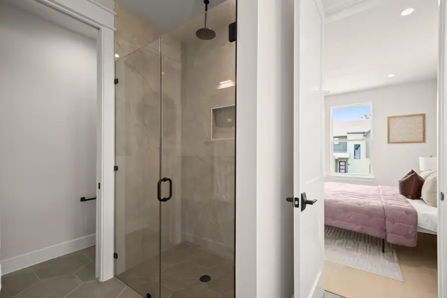Ensuite bathroom featuring a stall shower and light tile patterned floors