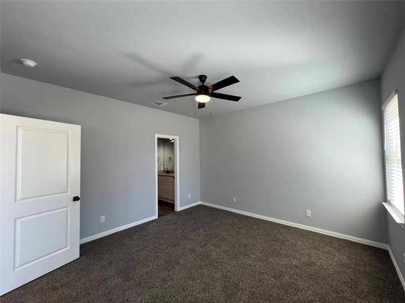 Unfurnished room with ceiling fan and dark colored carpet