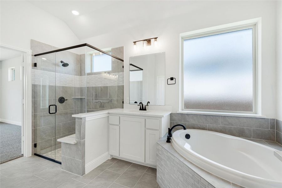 Master bathroom with glass walk-in shower, soaking tub, and white vanity with gray tile