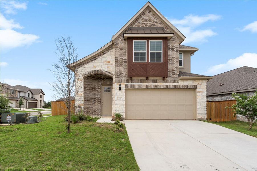 View of front facade featuring concrete driveway, an attached garage, stone siding, brick siding, and a standing seam roof View of front facade featuring concrete driveway, an attached garage, stone siding, brick siding, and a standing seam roof