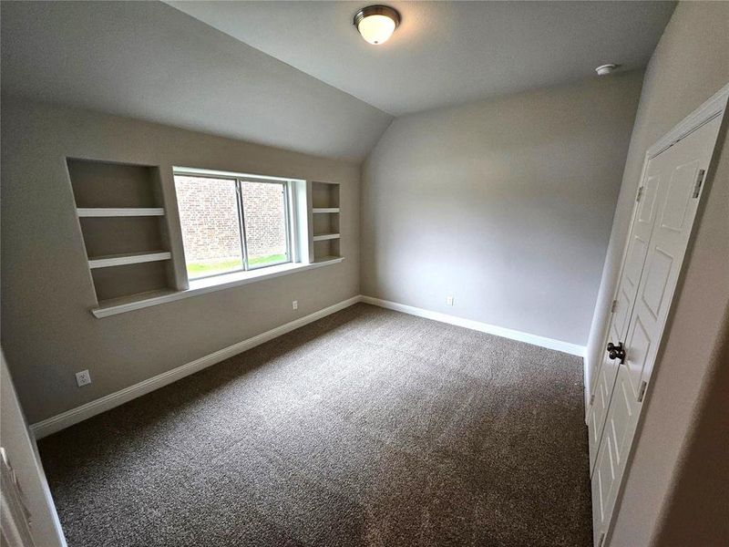 Bed 2 with built-in shelves, vaulted ceiling, and walk-in closet.