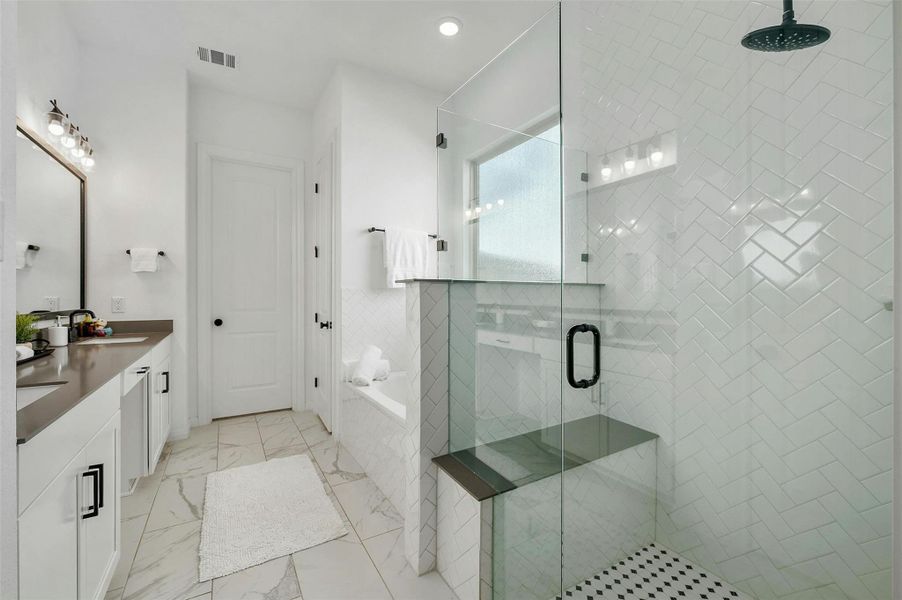 Soak off the day's stress in the relaxing built-in soaking tub and enjoy a sizable walk-in shower enclosed in frameless glass with designer tile surround, bench seating, and an overhead rain shower head.