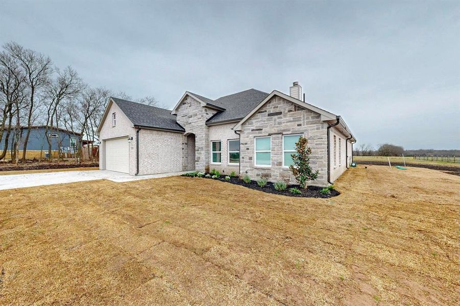 View of front of house with driveway, a front lawn, stone siding, a chimney, and an attached garage