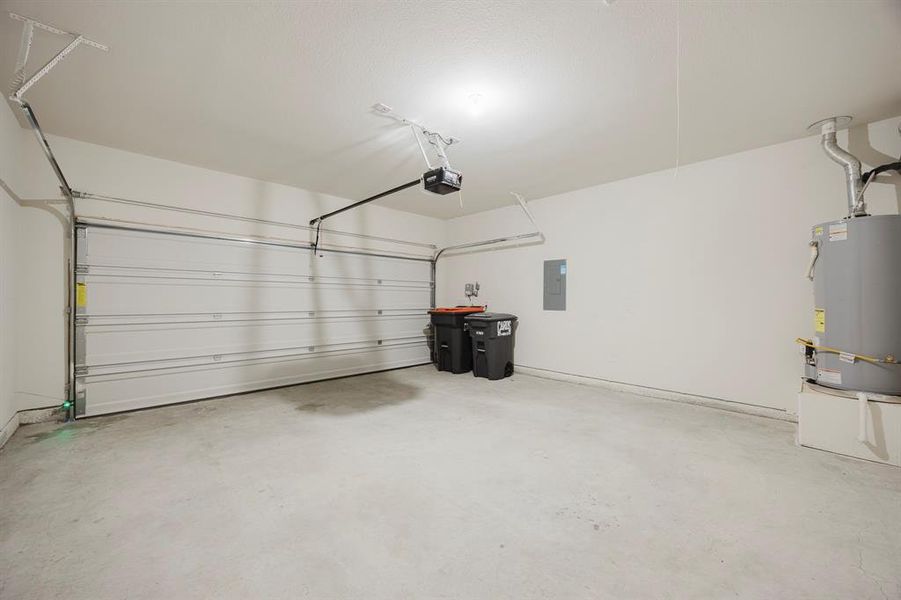 Garage featuring water heater, electric panel, and a garage door opener