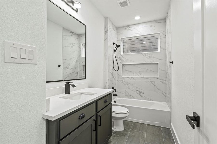 Bathroom featuring a textured wall, vanity, and a combined bath / shower with marble appearance Bathroom featuring a textured wall, vanity, and a combined bath / shower with marble appearance