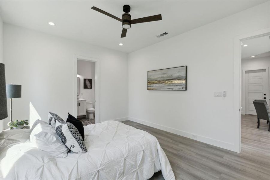 Bedroom with ceiling fan, ensuite bath, and hardwood / wood-style floors