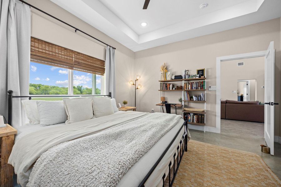 Bedroom with concrete flooring, a tray ceiling, ceiling fan, and recessed lighting