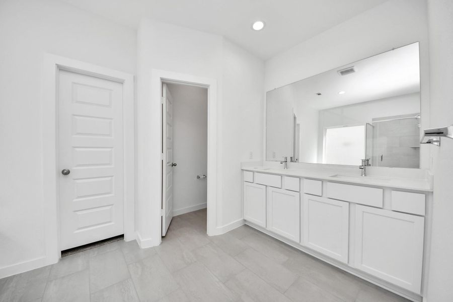 Escape to a spa-like oasis in this primary bathroom. Enjoy a walk-in shower with tile surround, a separate garden tub with custom detailing, and an elegant vanity featuring light countertops, modern hardware, and beautiful recessed lights. Experience luxury and relaxation in every detail. Sample photo of completed home with similar floor plan. Actual colors and selections may vary.