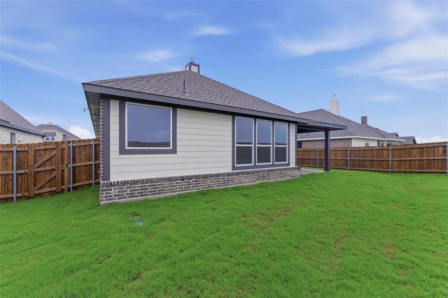 Expansive green lawn surrounds the property, featuring a durable wood privacy fence