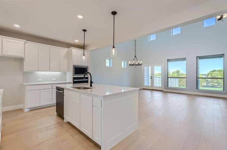 Kitchen featuring appliances with stainless steel finishes, white cabinetry, an island with sink, pendant lighting, and sink